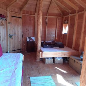 Cabane en bois chaleureuse avec lit douillet et décoration naturelle.