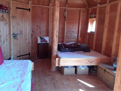 Cabane en bois chaleureuse avec lit douillet et décoration naturelle.