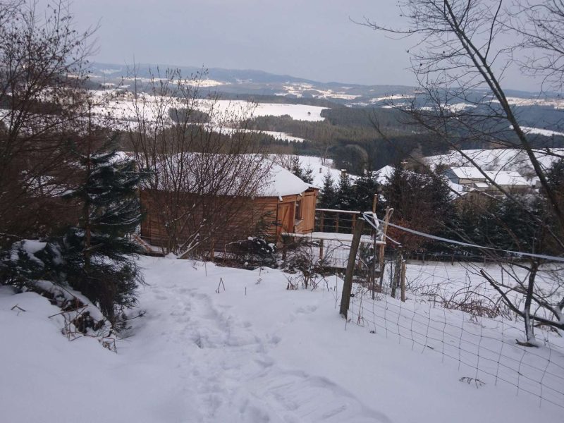 Hébergement insolite en bois en Auvergne, entouré de neige et de paysages vallonnés.