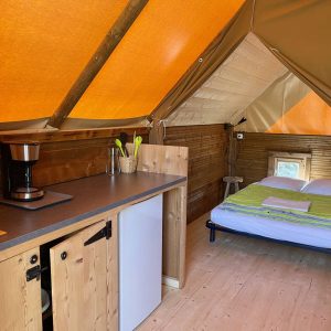 Tente lodge confortable en Auvergne-Rhône-Alpes, avec intérieur en bois et lumière naturelle.