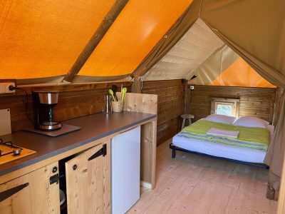 Tente lodge confortable en Auvergne-Rhône-Alpes, avec intérieur en bois et lumière naturelle.