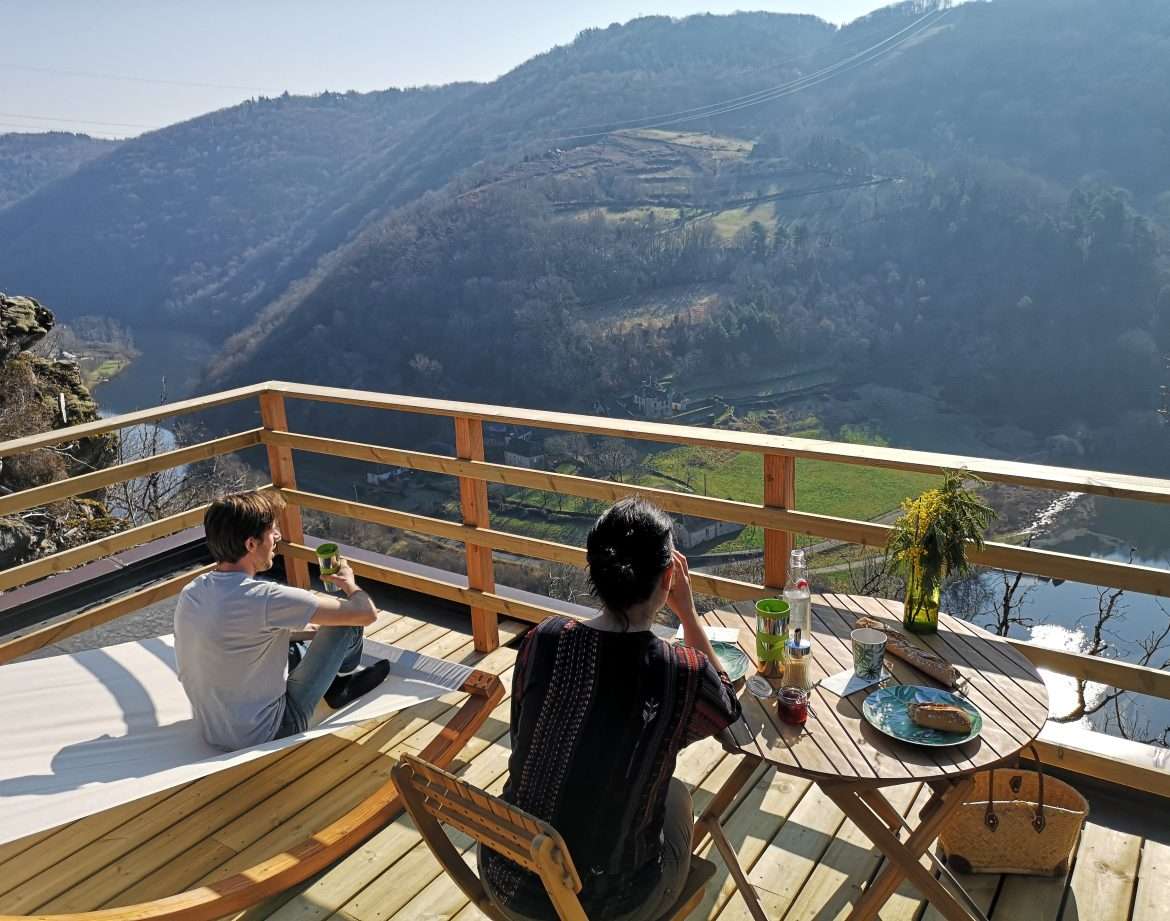 Cabane perchée avec vue panoramique sur la vallée et la rivière, moment de détente.