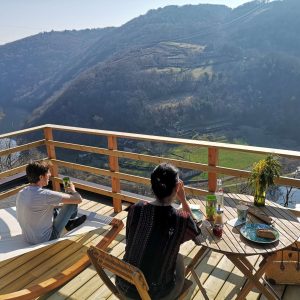 Cabane perchée avec vue panoramique sur la vallée et la rivière, moment de détente.
