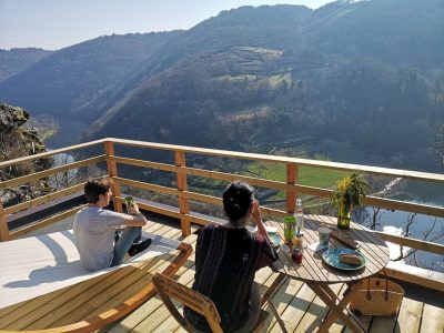 Cabane perchée avec vue panoramique sur la vallée et la rivière, moment de détente.