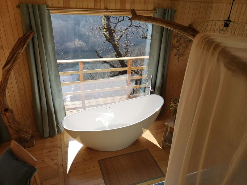 Cabane en bois avec baignoire design et vue sur la nature.