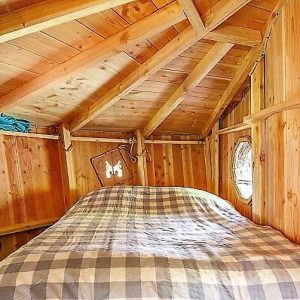 Cabane en bois cosy en Auvergne, avec lit douillet et fenêtres rondes.