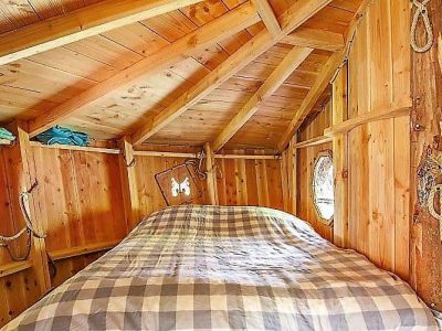 Cabane en bois cosy en Auvergne, avec lit douillet et fenêtres rondes.