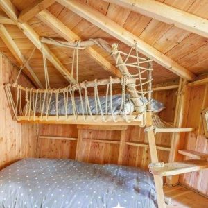Cabane en bois avec un lit suspendu et une décoration chaleureuse en Auvergne.