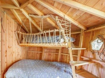 Cabane en bois avec un lit suspendu et une décoration chaleureuse en Auvergne.