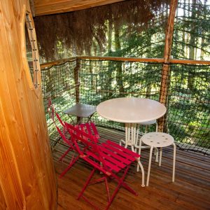 Cabane perchée en Auvergne avec terrasse en bois et chaises colorées.