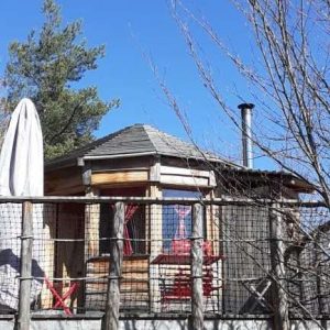 Cabane perchée en Auvergne, avec terrasse en bois et vue dégagée sur le ciel bleu.