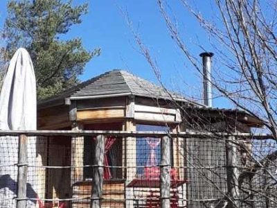 Cabane perchée en Auvergne, avec terrasse en bois et vue dégagée sur le ciel bleu.
