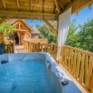 Hébergement insolite en Aquitaine avec jacuzzi sur une terrasse en bois, vue sur la nature.