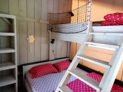 Chambre en cabane avec lits superposés et draps à pois rouges, ambiance cosy.