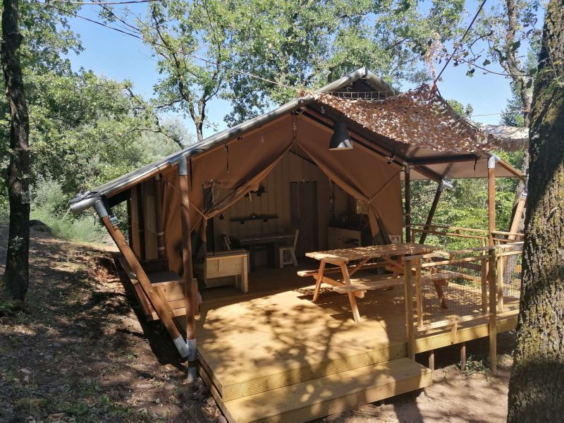 Tente lodge en bois avec terrasse, nichée dans la nature verdoyante du Languedoc-Roussillon.