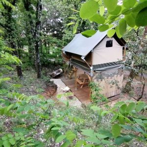 Cabane perchée en bois, entourée de verdure, offrant une expérience nature unique.