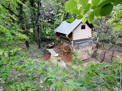 Cabane perchée en bois, entourée de verdure, offrant une expérience nature unique.