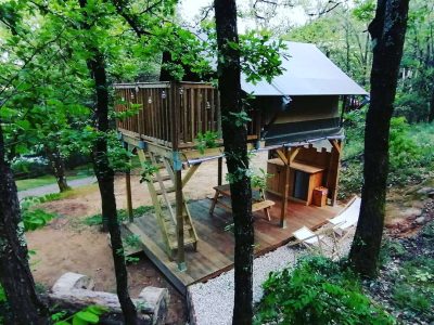 Cabane perchée en bois entourée darbres, offrant un cadre naturel apaisant.