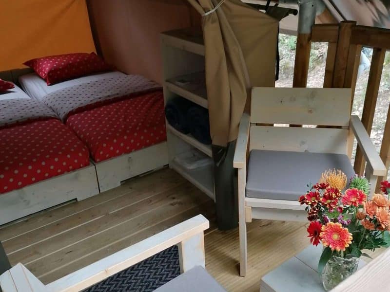 Tente glamping confortable avec lits douillets et coin salon en bois.