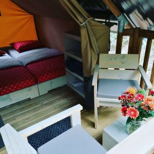 Tente lodge cosy avec lit douillet et coin salon, décorée de fleurs colorées.