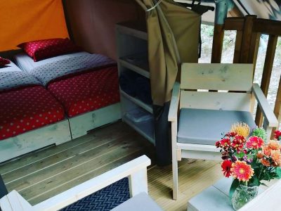 Tente lodge cosy avec lit douillet et coin salon, décorée de fleurs colorées.
