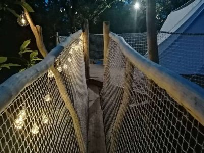 Hébergement insolite en cabane dans les arbres, chemin lumineux suspendu.