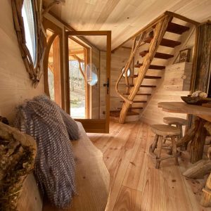 Cabane en bois avec un escalier en spirale et un intérieur chaleureux en bois naturel.
