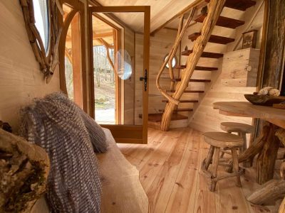Cabane en bois avec un escalier en spirale et un intérieur chaleureux en bois naturel.