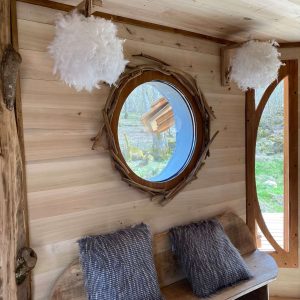 Hébergement insolite en Midi-Pyrénées, intérieur en bois avec miroir rond et coussins moelleux.