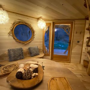 Cabane en bois à Midi-Pyrénées, avec fenêtres rondes et décor naturel chaleureux.