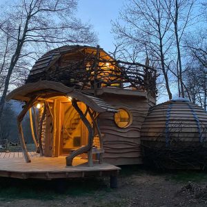 Cabane en bois originale à Midi-Pyrénées, illuminée, entourée darbres.