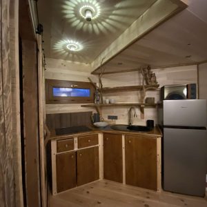 Hébergement insolite en Midi-Pyrénées, intérieur en bois avec cuisine équipée et éclairage design.