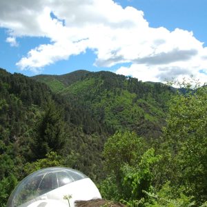 Hébergement insolite en bulle transparente, avec vue sur les montagnes verdoyantes.
