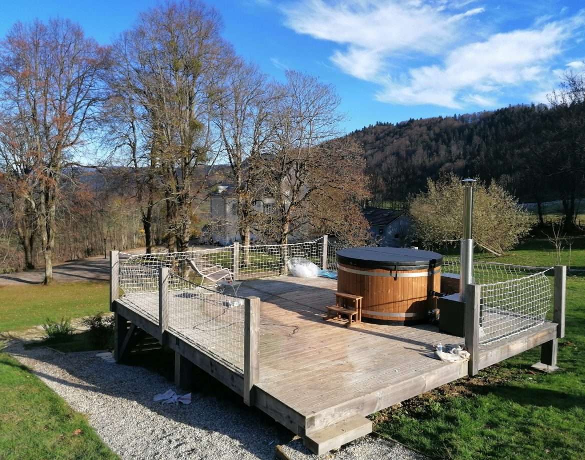 Hébergement insolite en Auvergne-Rhône-Alpes avec terrasse et jacuzzi en bois.