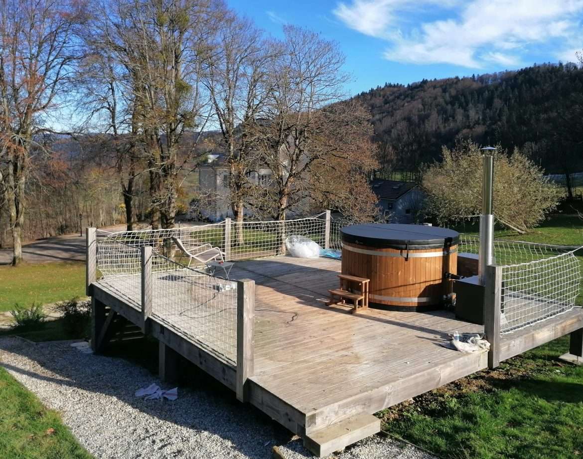 Hébergement insolite en Auvergne-Rhône-Alpes avec terrasse et jacuzzi en bois.