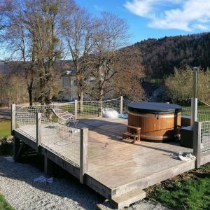 Hébergement insolite en Auvergne-Rhône-Alpes avec terrasse et jacuzzi en bois.