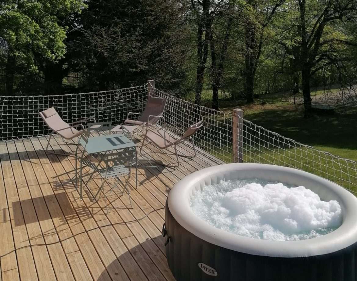 Hébergement insolite en Auvergne-Rhône-Alpes avec jacuzzi sur une terrasse en bois.