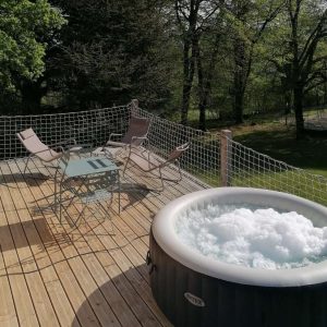 Hébergement insolite en Auvergne-Rhône-Alpes avec jacuzzi sur une terrasse en bois.