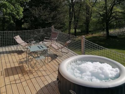 Hébergement insolite en Auvergne-Rhône-Alpes avec jacuzzi sur une terrasse en bois.
