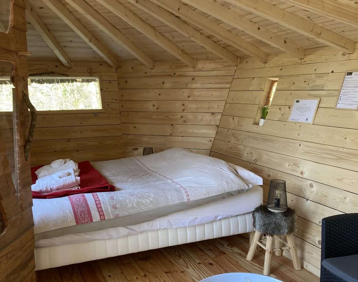 Cabane en bois cosy avec lit douillet et décoration chaleureuse.