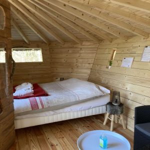 Cabane en bois cosy avec lit douillet et décoration chaleureuse.