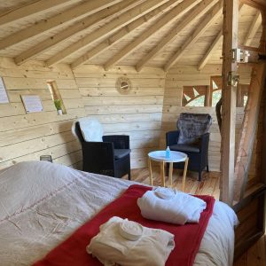 Cabane en bois cosy avec lit douillet et coin salon confortable.