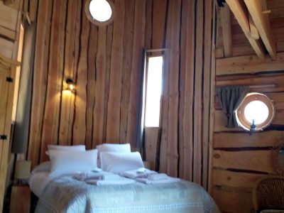 Chalet en bois dans les montagnes, avec un lit douillet et des fenêtres rondes.