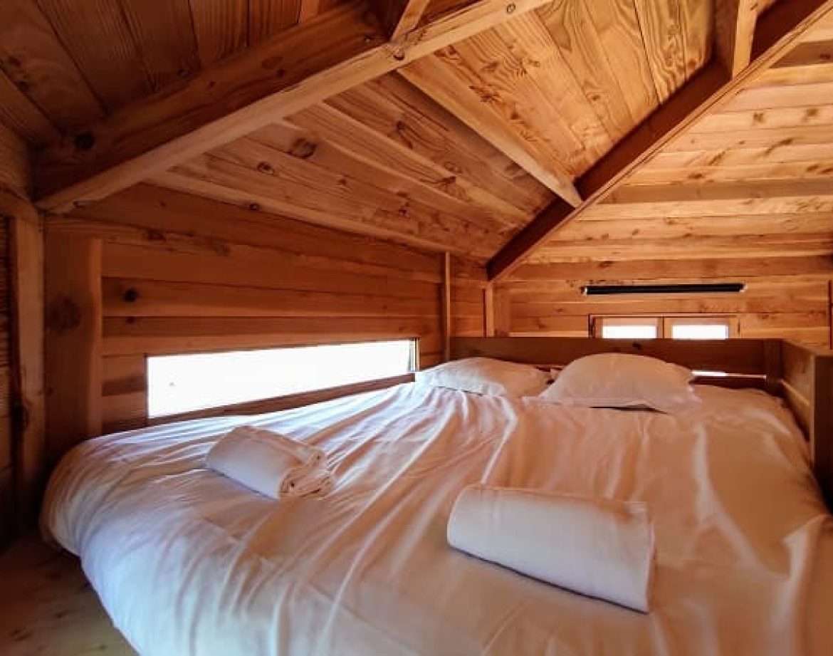 Chalet en bois chaleureux avec lit douillet et vue sur la nature.