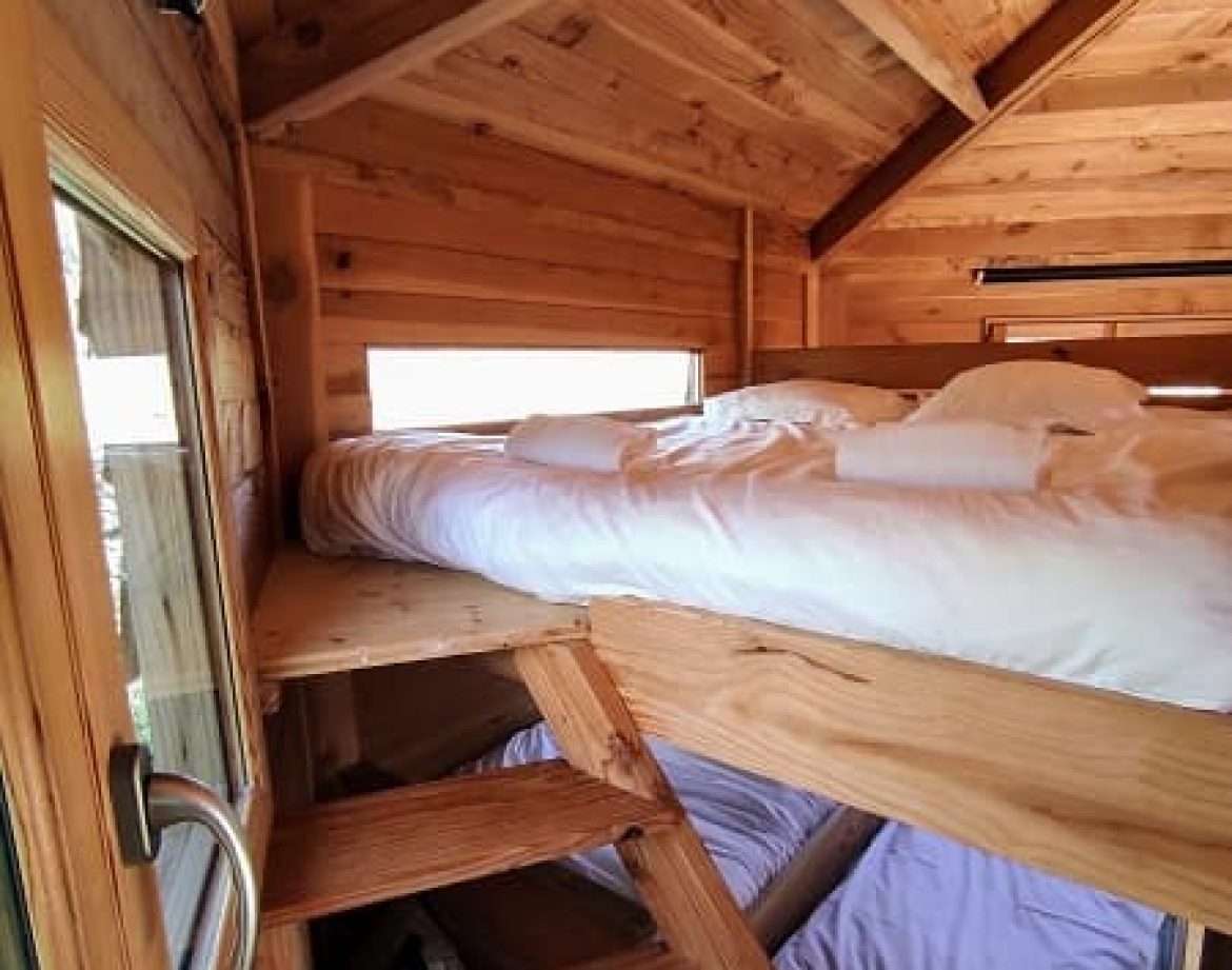 Cabane en bois avec mezzanine, intérieur chaleureux et lumineux.