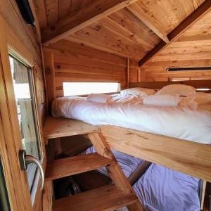Cabane en bois avec mezzanine, intérieur chaleureux et lumineux.
