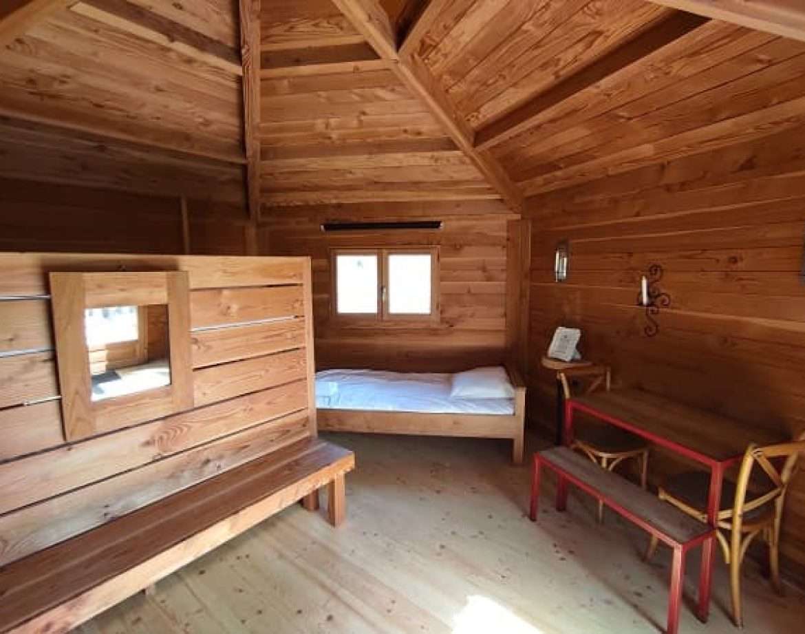 Cabane en bois au Centre, intérieur chaleureux avec lit simple et mobilier en bois.