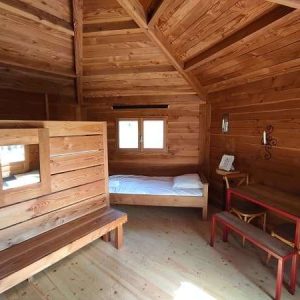 Cabane en bois au Centre, intérieur chaleureux avec lit simple et mobilier en bois.