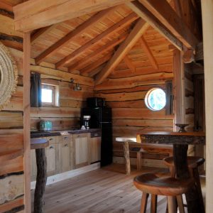 Cabane en bois dans les montagnes, intérieur chaleureux avec cuisine et table en bois.