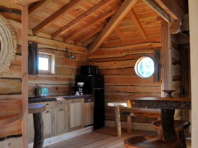 Cabane en bois dans les montagnes, intérieur chaleureux avec cuisine et table en bois.